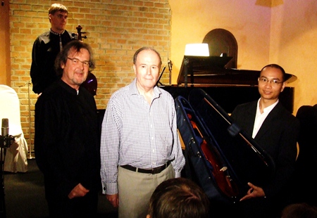 Composer Richard Harvey, left, and SCO co-founder John Pawson, center, stand with Chiang Rai Youth Orchestra’s Paramet Lertkasem after he is presented with the new musical instruments.