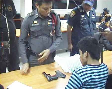 Nopporn Kesatcha (seated) is asked to give an explanation for the 11mm. pistol found in his possession.