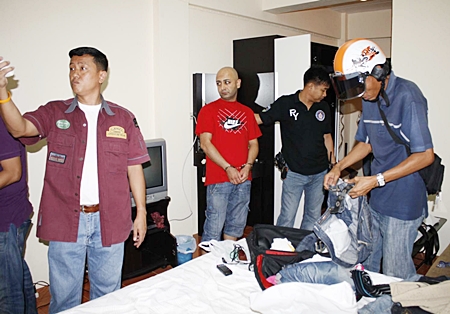 Iranian Asghar Haji Khan Mirzaci, center, looks on as police search his room at the Niran Condominium complex for stolen property.