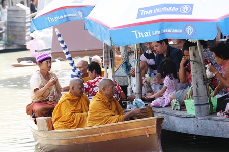 Monks arrive by boat to receive alms at Pattaya’s Floating Market.