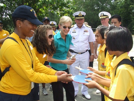 Sailors help Ambassador Kenney distribute sports equipment to local students.
