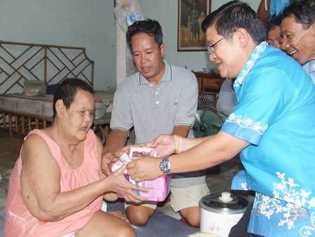 (L to R) Buoy Kritthawin, and her son Chairat accept help from Deputy Mayor Verawat Khakhay and the mobile medical team. 