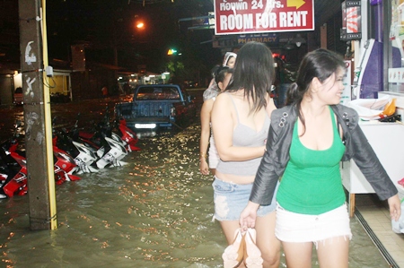 No motorbike taxi here - Women walk past inundated motorcycles as they try to make it home during overnight flooding.