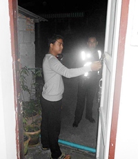 Owner Thanakit Sae-Ung inspects the back door, used by thieves to break into his office. 