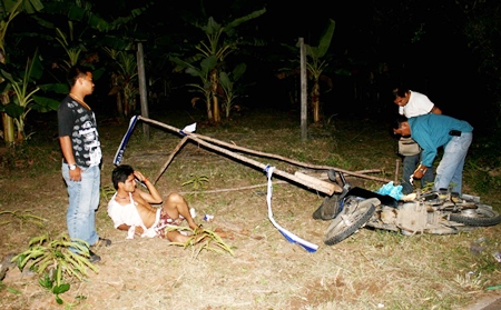 Narong Hinon lays on the ground as police search his motorcycle for drugs. 