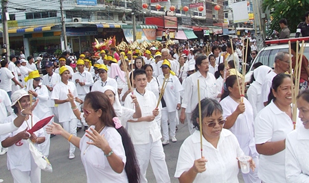 White clad participants in the opening day parade make their way through the streets.