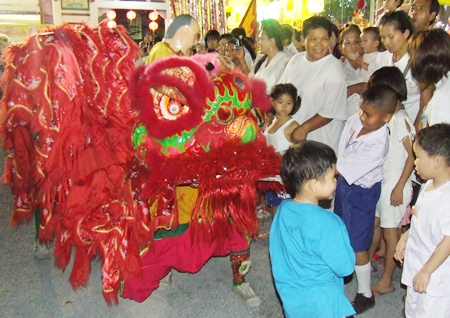 A ferocious red lion excites the youngsters during the festivities.