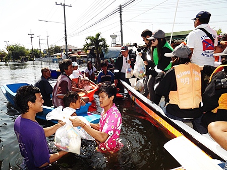 Victims wade through chest deep water to receive aid packages from the Pattaya crew.