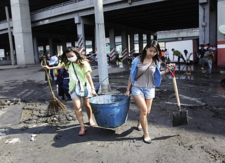 Volunteers carry a bucket full of mud during a clean-up drive after floodwaters receded from Bangkok, Saturday, Nov. 19. Hundreds of city workers, police, army personnel and civilian volunteers have been working to dig out the mud from previously flooded areas in the Big Mango. The situation has improved dramatically in recent days and cleanup has begun in many areas, though some still face weeks more under water. The government said 17 provinces remained flooded Sunday. They also said Sunday that the death toll has reached 602, the majority from drowning. (AP Photo/Altaf Qadri) 