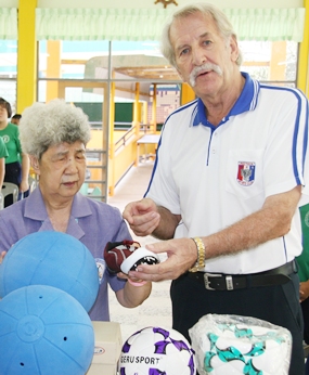 William Macey, charity chairman of the Pattaya Sports Club, presents sports equipment to Aurora Sribuaphan, Principal of the School for the Blind. 