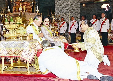 His Majesty the King observes an ancient ritual by receiving lustral water and sacred leaves from the Chief of the Brahmin Court as Her Majesty the Queen looks on at the Grand Palace in Bangkok, Saturday, June 10, 2006.