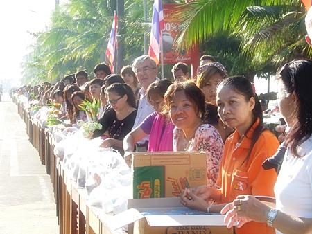 Thousands of residents line Jomtien Beach Road offering alms to monks and having lustral water sprinkled on them. 