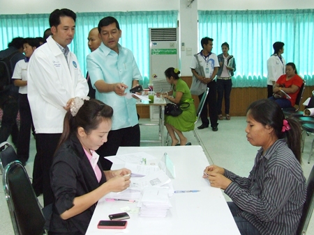 Banglamung District Chief Chawalit Saeng-Uthai (standing center) and Pattaya Mayor Itthiphol Kunplome (left) preside over the distribution of compensation for damage caused by local flooding in September and October. 