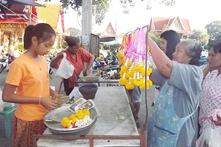 A young vendor prepares to sell her garlands so that people can make merit on Makha Bucha Day.