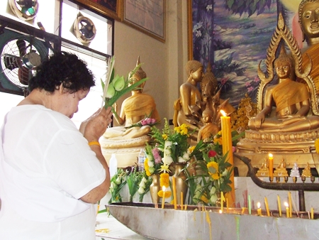 Lighting candles and making an offering to Buddha at Wat Nong - Or, Central Pattaya early morning on Makha Bucha Day.
