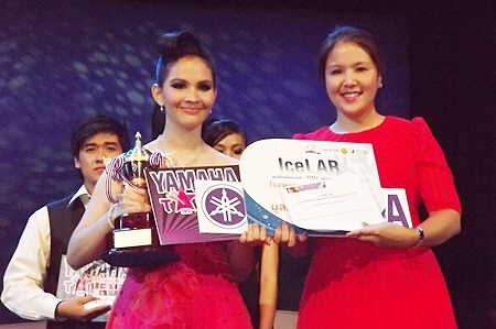 Phathakan Samertwet (left) from Pattaya School No. 11 receives her prize for winning the Thai or International singing category for teenagers, from Darin Phanthusak, director of Siam Kolakarn School. 