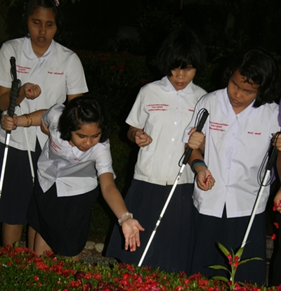 The blind students sprinkle rose petals on Father Ray’s final resting place.