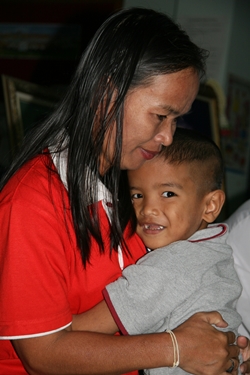 A little boy from the Children’s Village seems happy in the arms of his mother.
