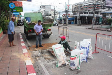 Workers in Soi Naklua 16/1 fix the collapsed drainage lids. 