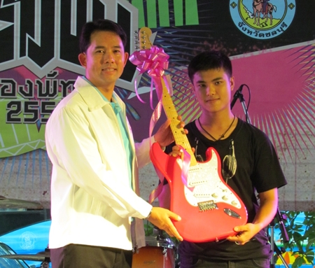 Mayor Itthiphol Kunplome (left) presents the outstanding guitarist award to Thummarat Uyatrakul from Awaken (right); an electric guitar from Sound House Life and Studio Pattaya
