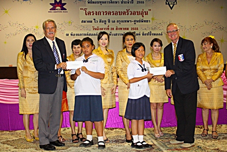 William Macey (left), charity chairman and Tony Oakes (right), president of the Pattaya Sports Club, present scholarships to youths.