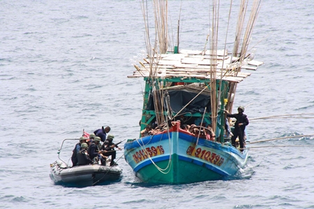 Enforcement officers from Royal Thai Navy patrol ships move in and secure a Vietnamese fishing boat caught illegally fishing in Thai waters. 