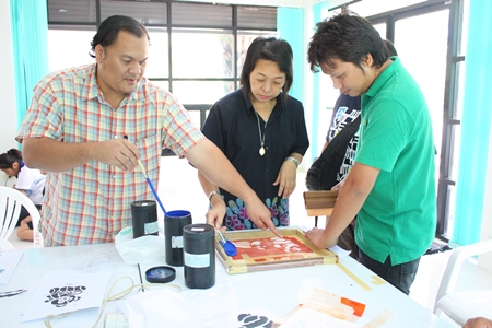 Wiroj Phadungket (left) and Wasana Changmuang (2nd left), experts on fabric printing, demonstrate techniques of coloring. 