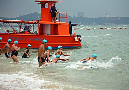 Swimmers begin the 1.2 km competition in heavy rain.