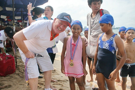 Rotary Jomtien-Pattaya PP Gudmund Eiksund presents medals to children competing in the Fun Swim for families, children and youths.