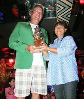 Ross Schiffre wears the champion’s green jacket as he receives the winner’s trophy from Mamasan Ead. 