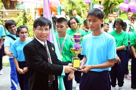 Suphamit Srikanthamakul, deputy director of the Chonburi Office of Primary Education Region 3, presents the winning cup to the blue team.