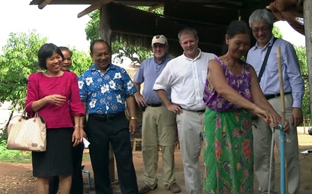 An overjoyed villager turns on the tap for the first time, much to the delight of Rotarians from both countries.