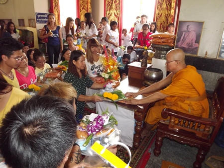Buddhists present Sanghathan and other items to monks at Wat Chaiyamongkol.