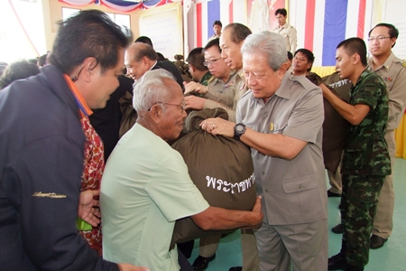 Privy Councilor Gen. Surayud Chulanont, representing the Their Majesties the King and Queen, presents aid bags to Koh Si Chang residents in need.