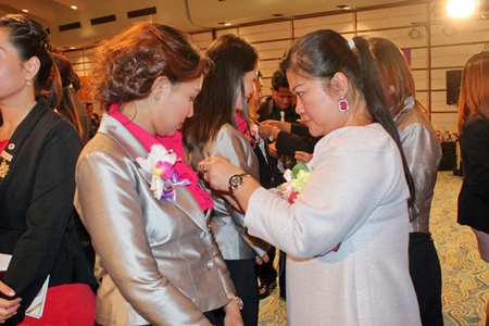 Members pin brooches on new 30 members during the candle lighting ceremony.