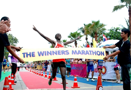Joseph Kariuki of Kenya celebrates with arms aloft as he crosses the finish line to win the 2013 King’s Cup Pattaya Marathon, Sunday, July 21.  African athletes filled the top seven positions in the men’s division and the women’s race was also won by a Kenyan athlete, but the event was more a celebration of spirit and fortitude as runners of all ages and nationalities took to Pattaya’s streets to face their own personal sporting challenges.   (PM Photo/Phasakorn Channgam)