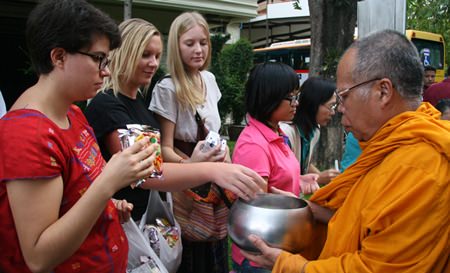 Foreign volunteers give alms to the monks.