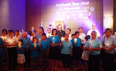 Centara Grand Mirage Beach Resort Pattaya GM Robert John Lohrmann (back row, center) leads employees, administrators, elders from Banglamung Elderly Center and children from Father Ray Children’s Village to light the candles in honor of HM the Queen on her 81st birthday.
