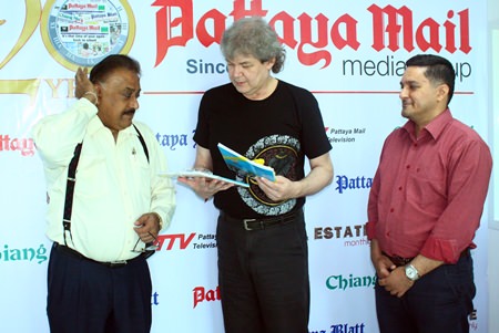 Pattaya Mail Media Group Managing Director Pratheep “Peter” Malhotra (left) and General Manager Kamolthep “Prince” Malhotra (right) present Hucky with commemorative books honoring HM the King of Thailand.  Hucky has transposed many of His Majesty’s musical compositions for the guitar. 