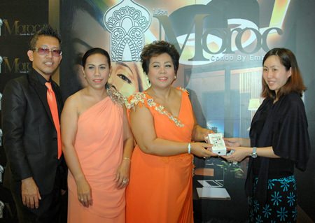 Sukanya Klayhong (center), Executive Manager of the Moroc Condo project, presents an iPhone 5 to a customer who registered on the official launch day, Oct. 20.