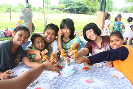 Children showing off their favorite chicken wings distributed by Hilton Hotel, Pattaya, for lunch at Child Protection and Development Center.