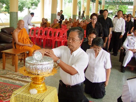 Phra Thep Suttajan, head of the province’s monk committee and abbot of Khao Bangsrai Temple (left) looks on as mourners take part in the water-ablution ceremony for the former Supreme Patriarch.