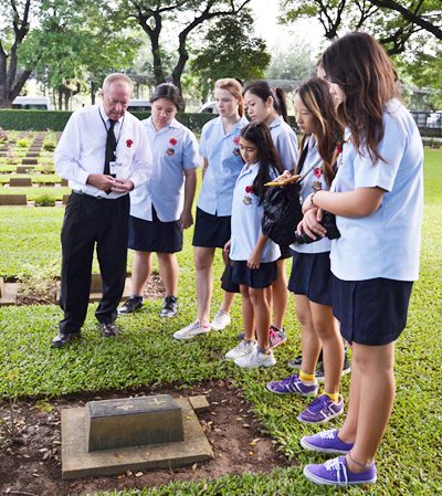 GIS students stand by a grave at the War Cemetery in Kanchanaburi.