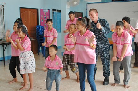 Everyone is having a great time when sailors from the USS Mustin dance with the children.