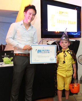 Executive Director of Royal Cliff Hotels Group, Vitanart Vathanakul, presents a certificate and special pumpkin loot bag for “Best Halloween Costume” to Sava “the little wizard”.