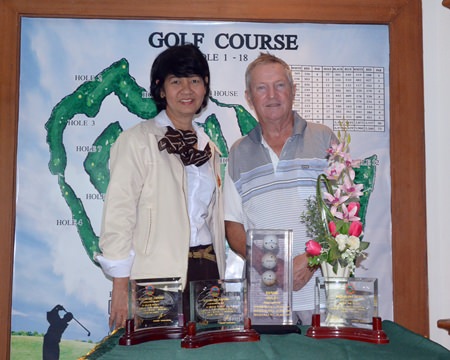 Bob Pearce (right) poses for a photo with Jintana Poonchai (left) of the Pattaya Country Club management team.  In front of Bob are his three individual hole-in-one trophies plus the unique ‘ball tower’.