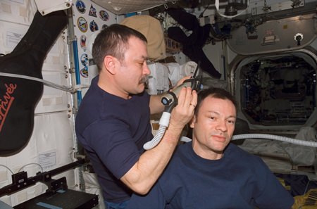 Cosmonaut Mikhail Tyurin, trims commander Michael E. Lopez-Alegria’s hair in the Unity node of the International Space Station. Tyurin used hair clippers fashioned with a vacuum device to garner freshly cut hair.