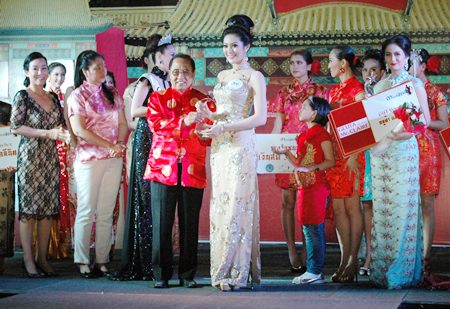 Chusak Sriwacharapong, city council member and chairman of the event, presents the winning trophy to Miss Qipao 2014, 24 year old Getmoli “Fai” Rojanapradit.