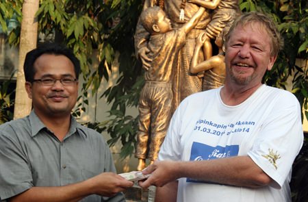 Khun Pae, Manager of the Drop-In Center, accepts the donation from Gizmo.