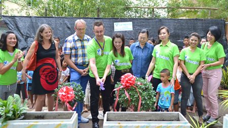 Nigel Quennell and Praichit Jetpai cut the ribbon to officially launch the project, whilst Maggie Travis (2nd left), Russell Iffland (3rd left), Sister Kanyanee Tuanrussmee (4th right), and Nicha Loychun (2nd right), along with YWCA members, Fountain of Life staff and children cheer them on.